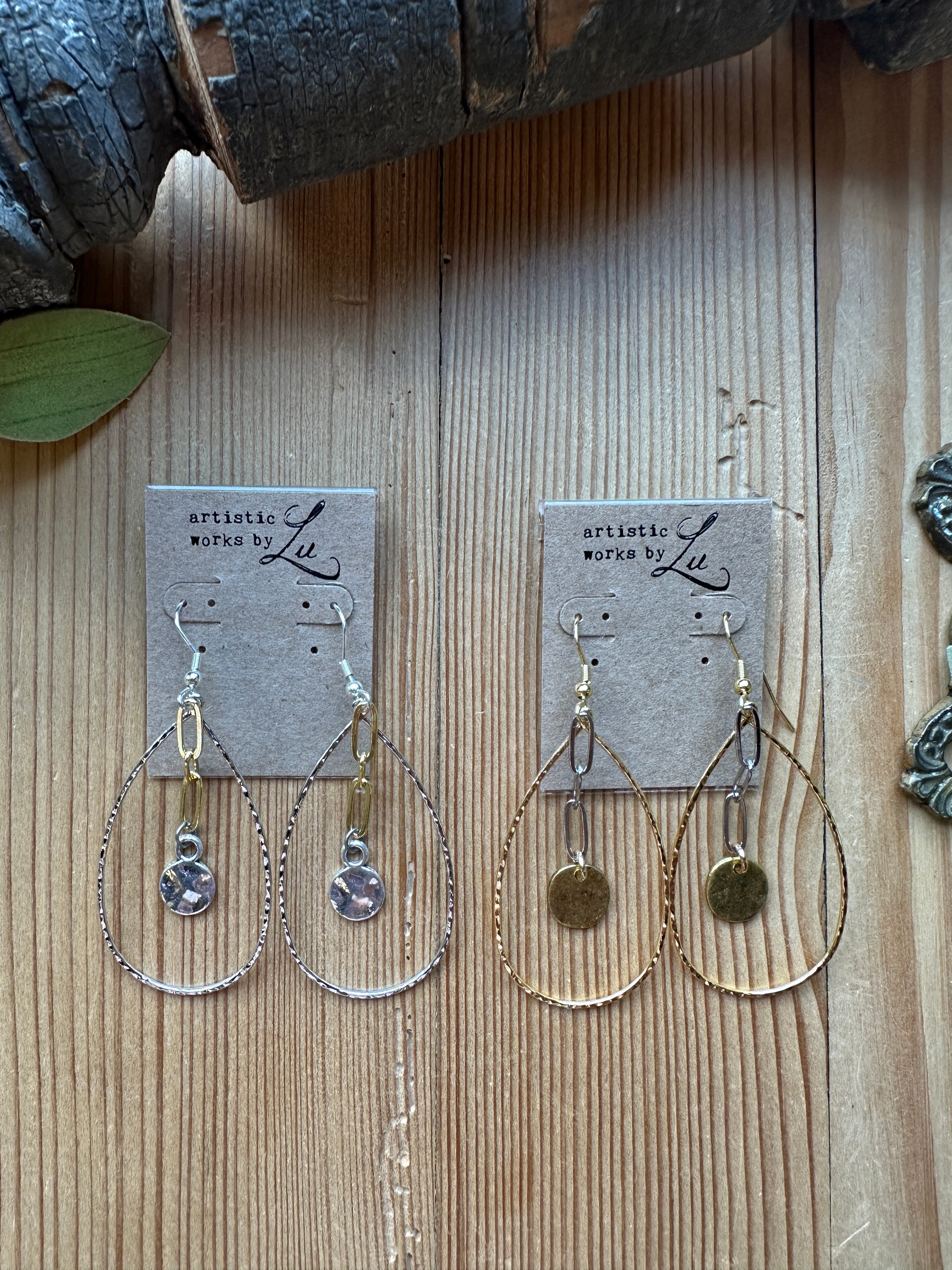 Gold hoop earrings on a wooden surface with an artistic works by lu card 