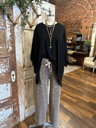 Mannequin wearing black flowy top and patterned leopard print pants and handmade jewelry against a rustic boutique springfield, mo