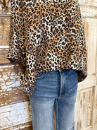 Mannequin wearing a leopard print collared top with and blue jeans against a rustic wooden background