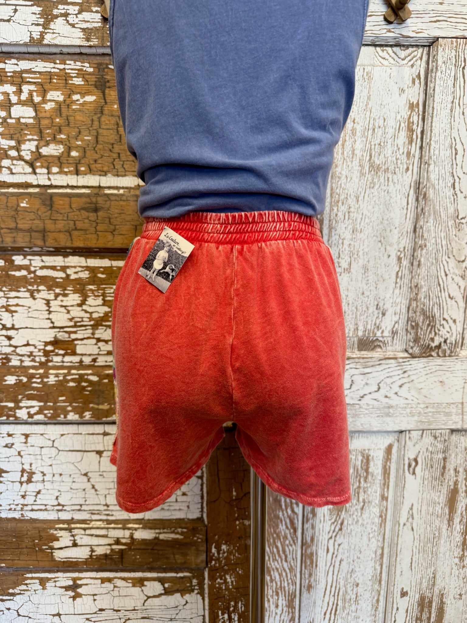 Person wearing red shorts with a blue shirt against a wooden background