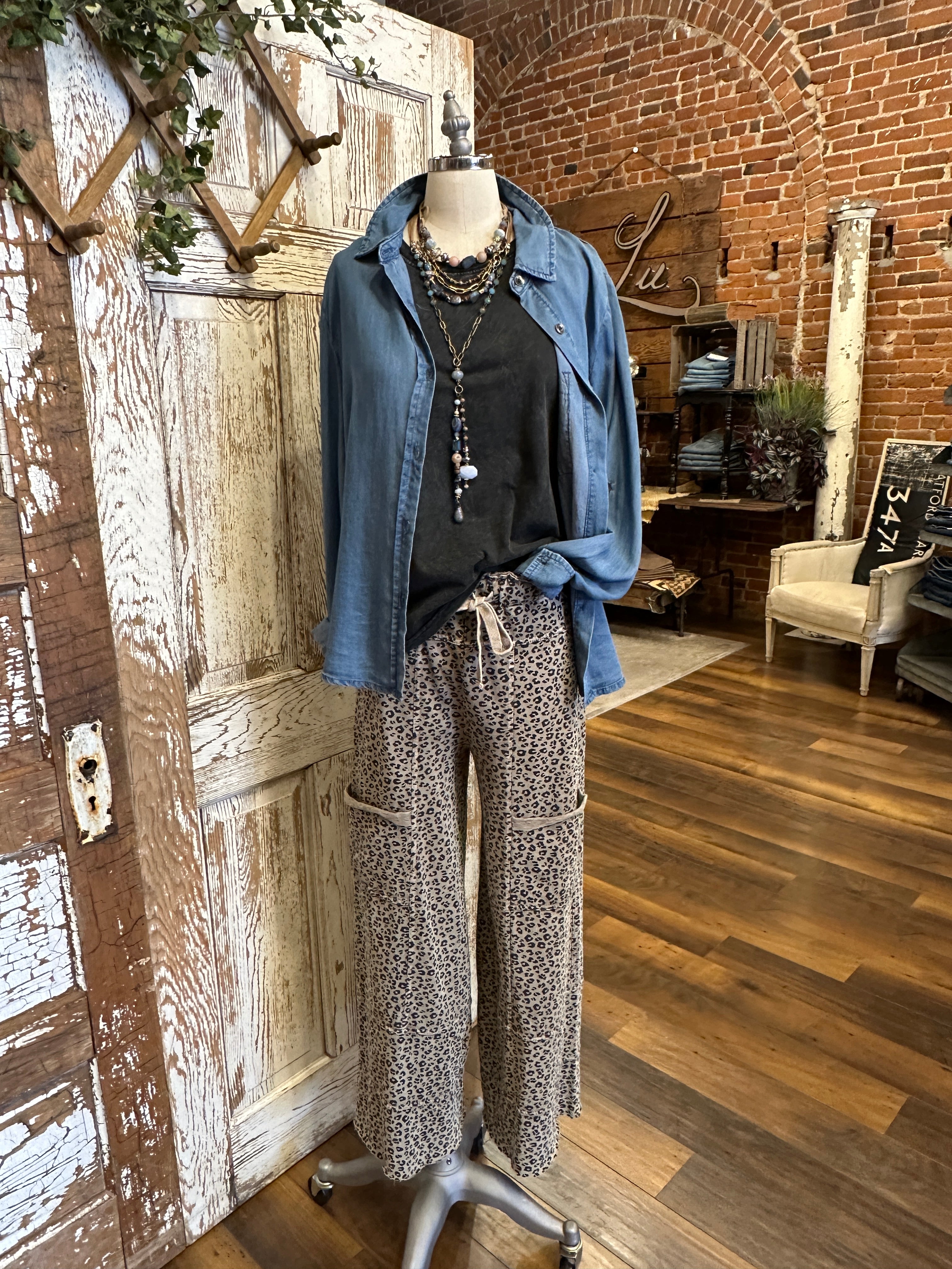 Mannequin wearing black tank and patterned leopard print leisurewear pants with handmade jewelry in a rustic boutique springfield, mo