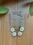 Gold-tone dangle earrings with white enamel K and C initial charms and paperclip link on an Artistic Works By Lu earring card