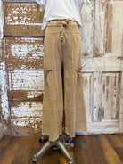 Beige cargo pants on a mannequin against a rustic wooden door background