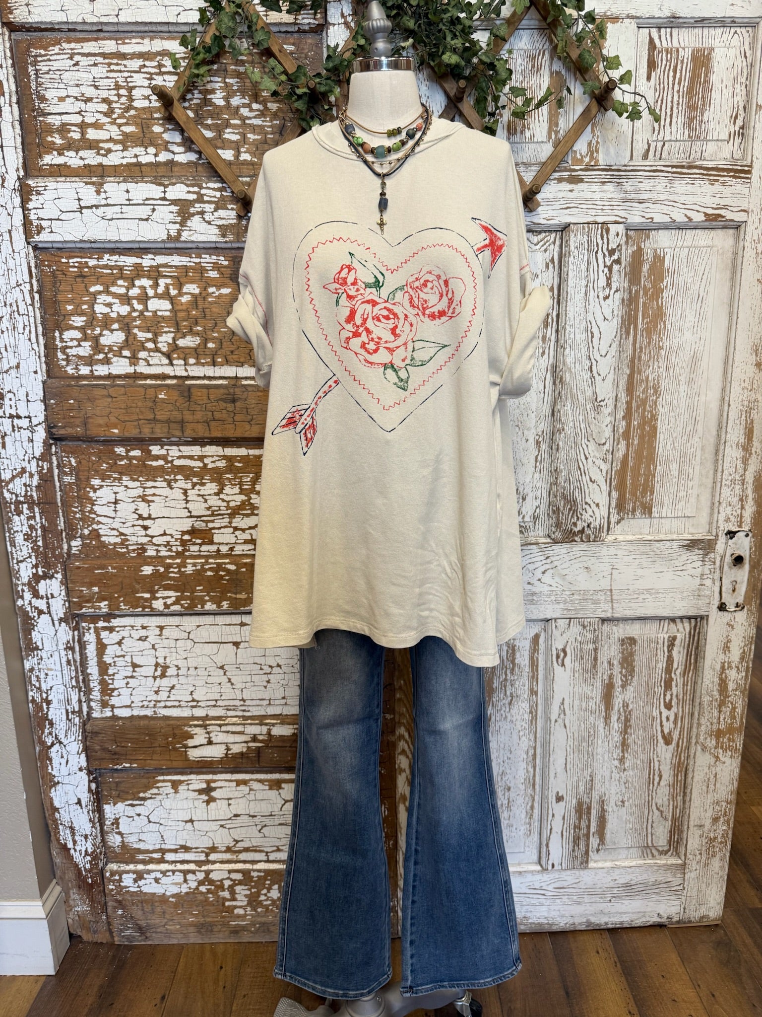 Mannequin wearing a cream graphic tee with floral heart design and jeans with handmade necklaces in Springfield, MO boutique