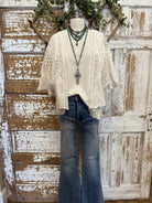 Mannequin wearing a white lace top and blue jeans with a cross pendant handmade necklace against a rustic wooden background
