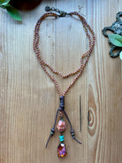 Pink necklace with beads and a pendant on a wooden surface
