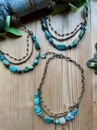 Handmade turquoise beaded necklaces with chain and leather on a wooden surface.