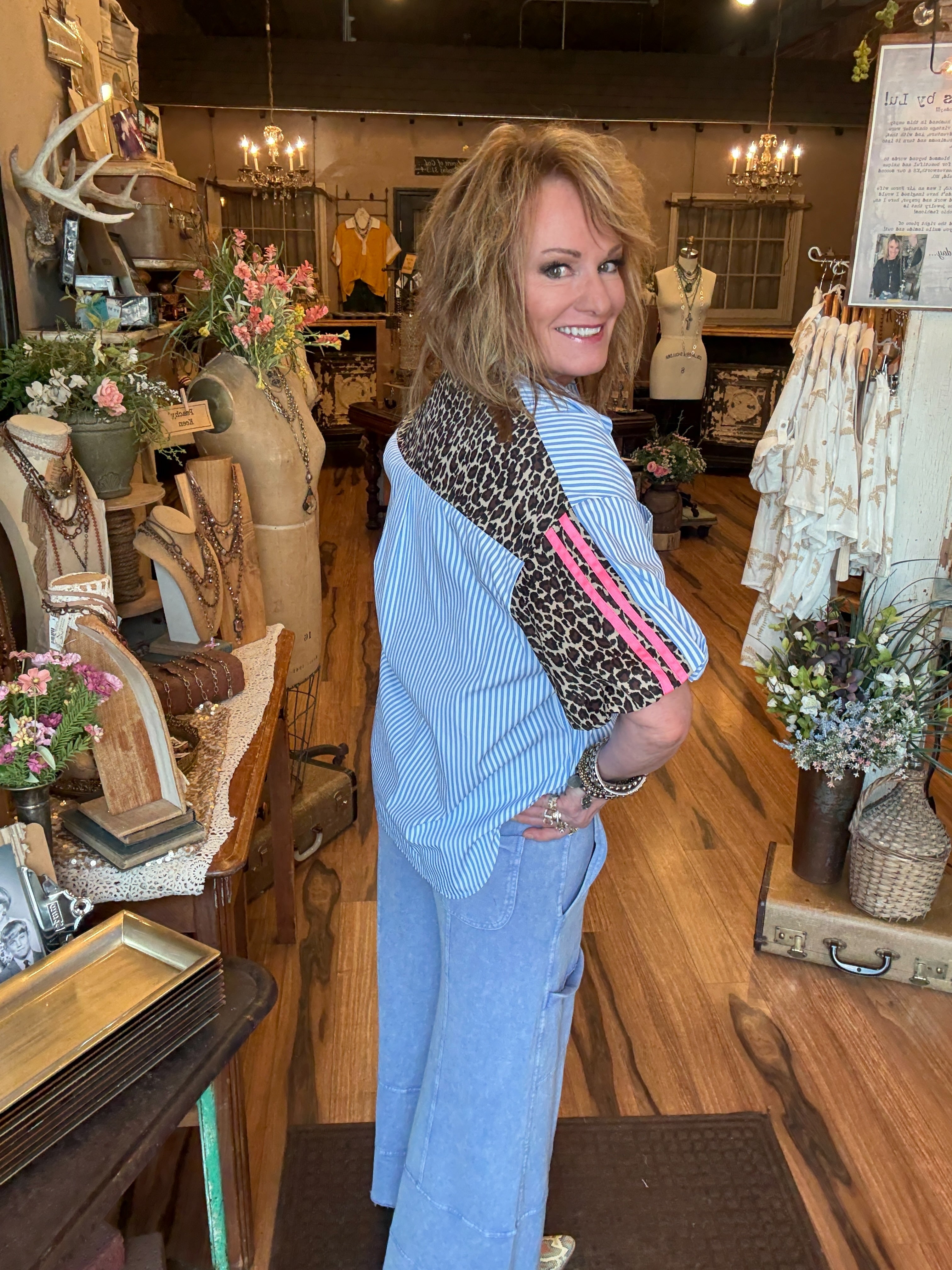 Lu wearing striped blue shirt with pink and leopard details and loungewear pants with lots of handmade jewelry in Leavenworth, KS boutique 