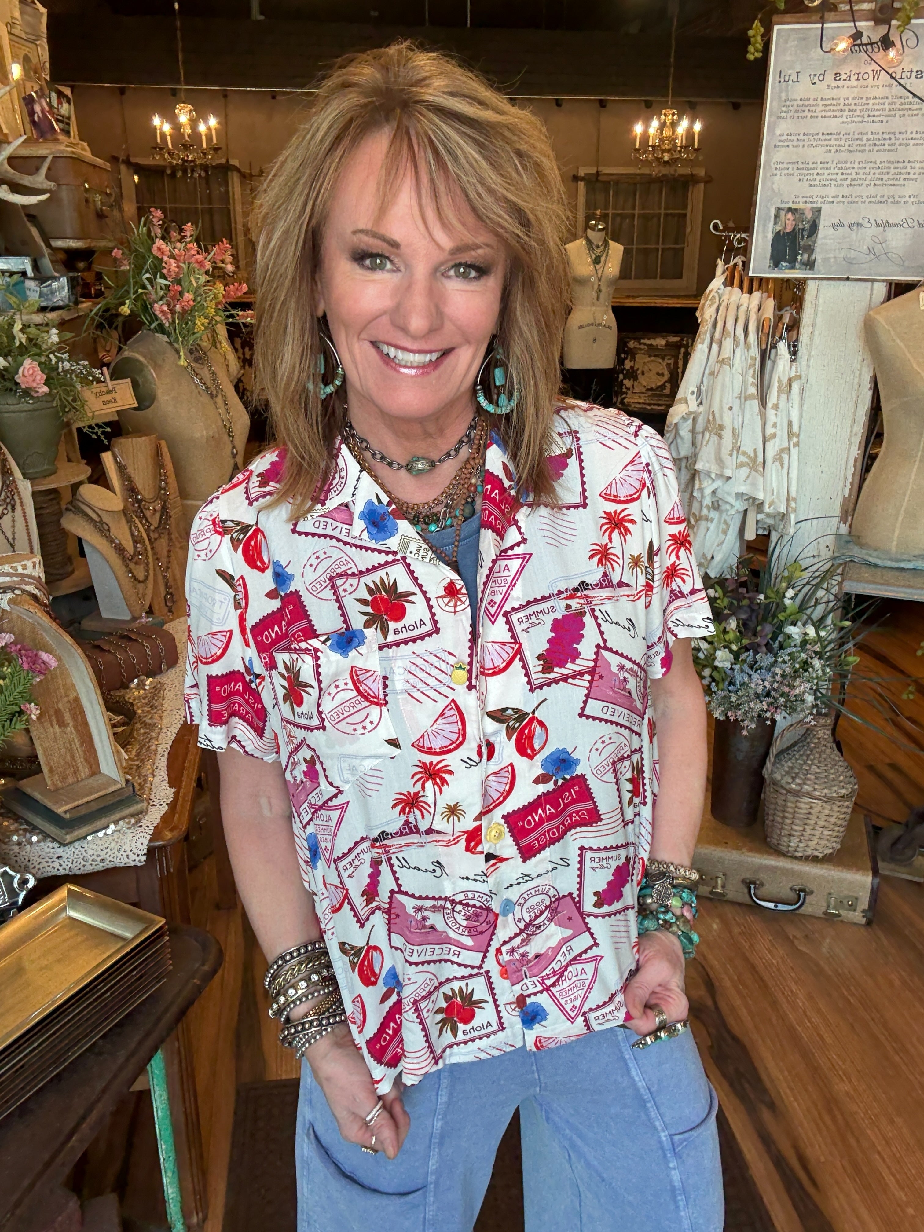 Lu wearing a colorful patterned camp shirt and handmade jewelry in a Leavenworth, KS boutique 