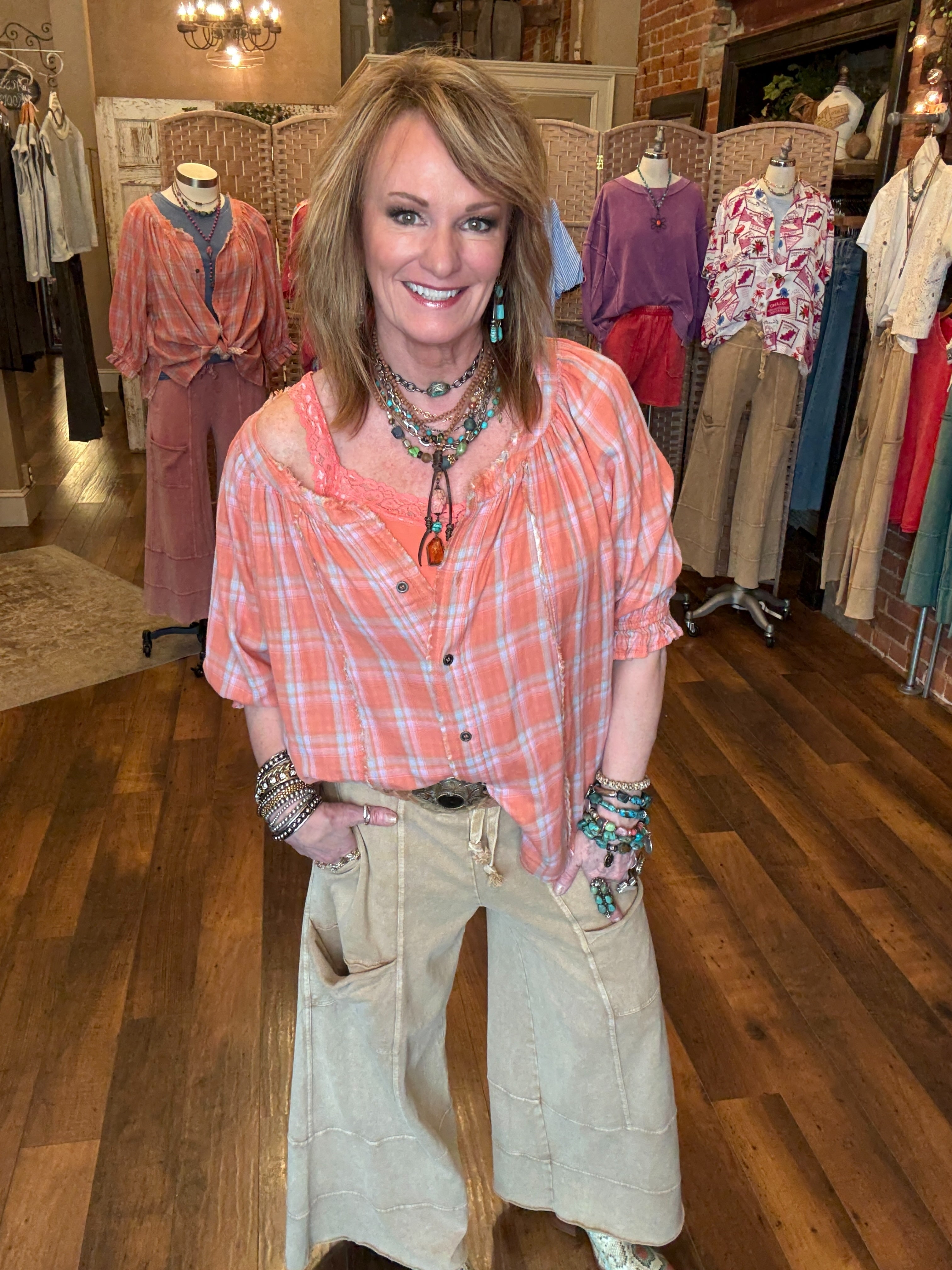 Lu wearing an orange and pink plaid shirt, handmade necklace and lounge wear in Leavenworth, KS boutique