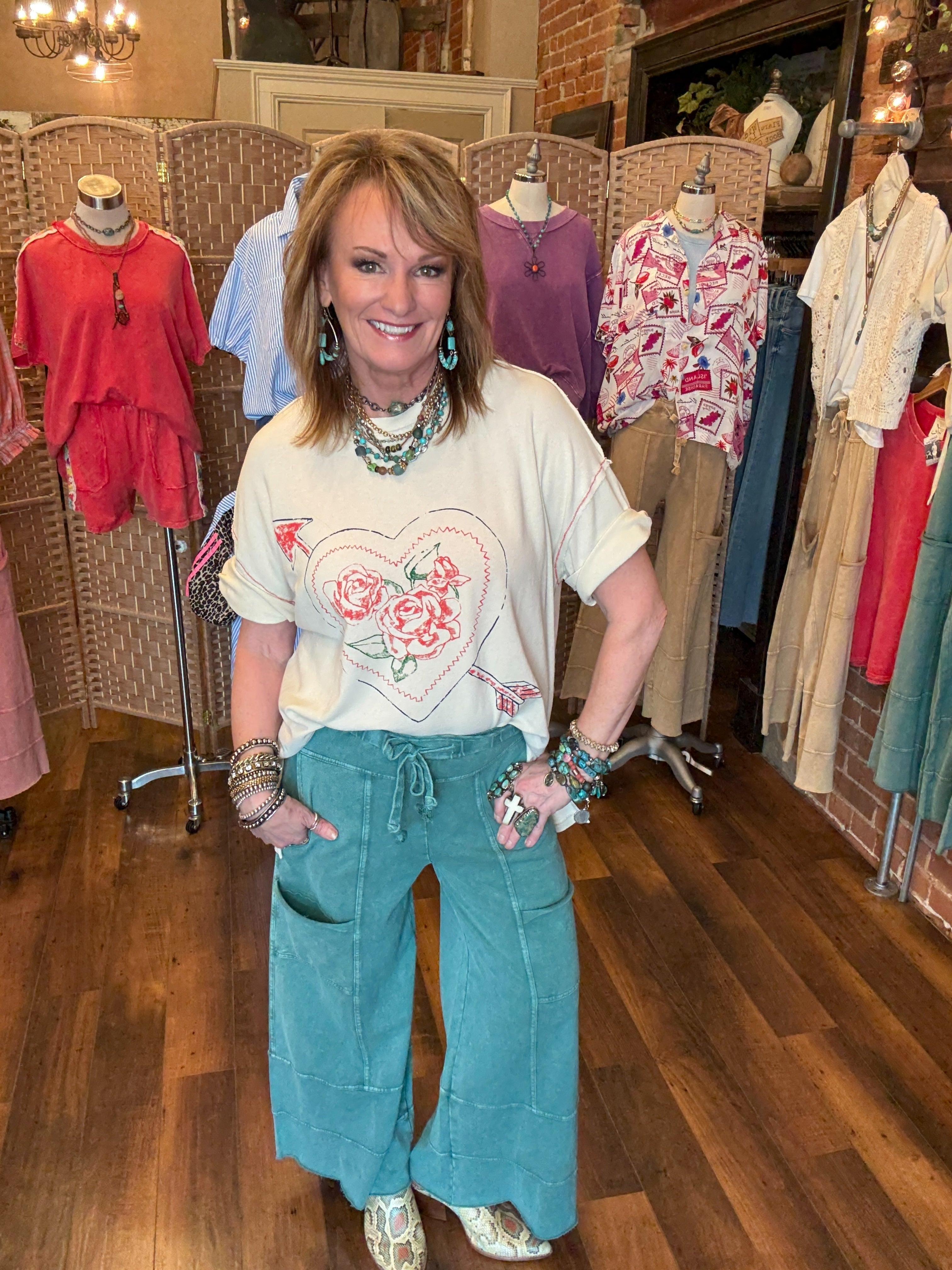 Lu in her boutique clothing store wearing a floral graphic t-shirt and teal leisurewear pants.