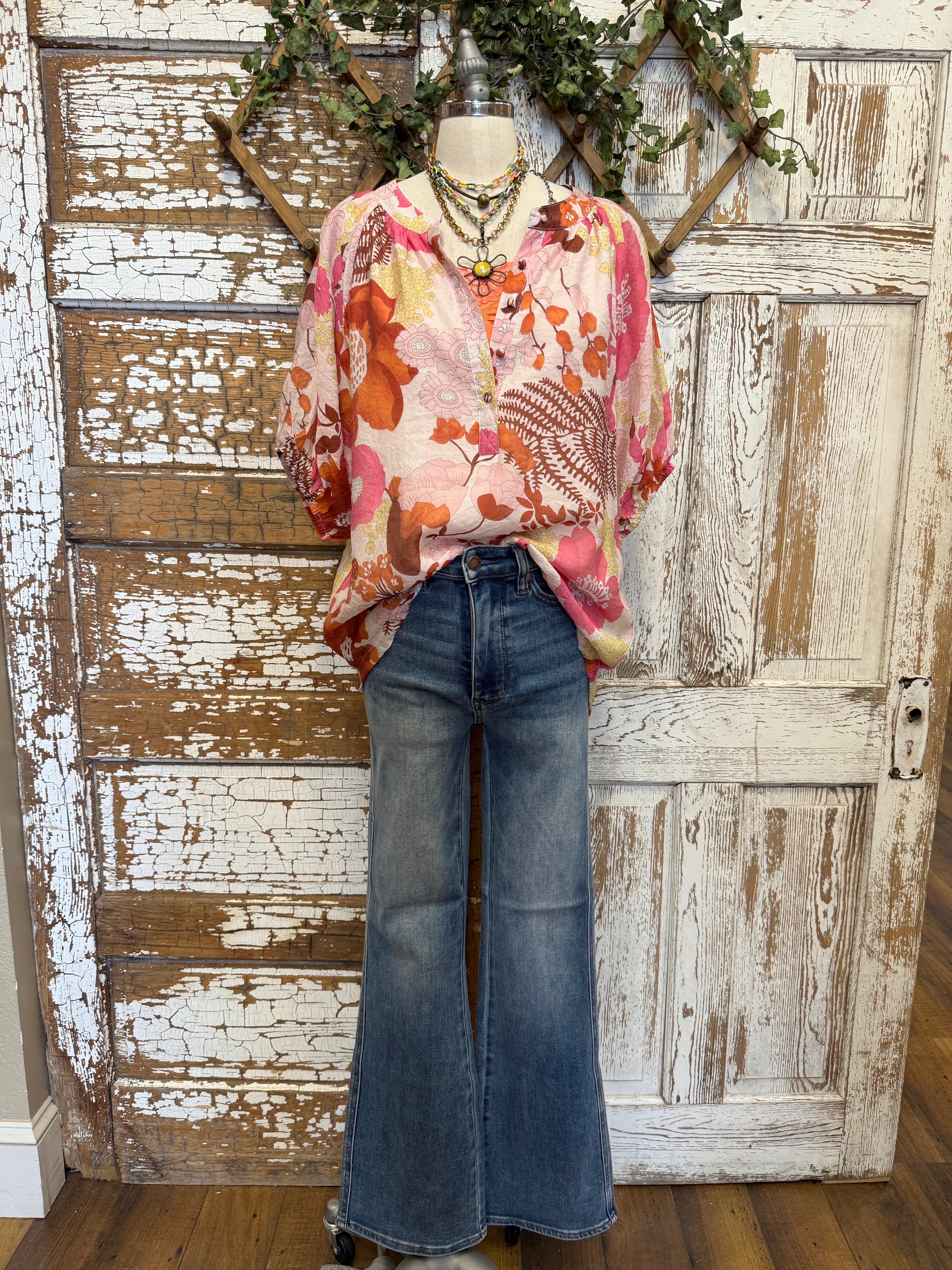 Mannequin wearing a floral blouse and jeans with handmade jewelry layers 