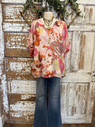 Mannequin wearing a floral blouse and jeans with handmade jewelry layers 