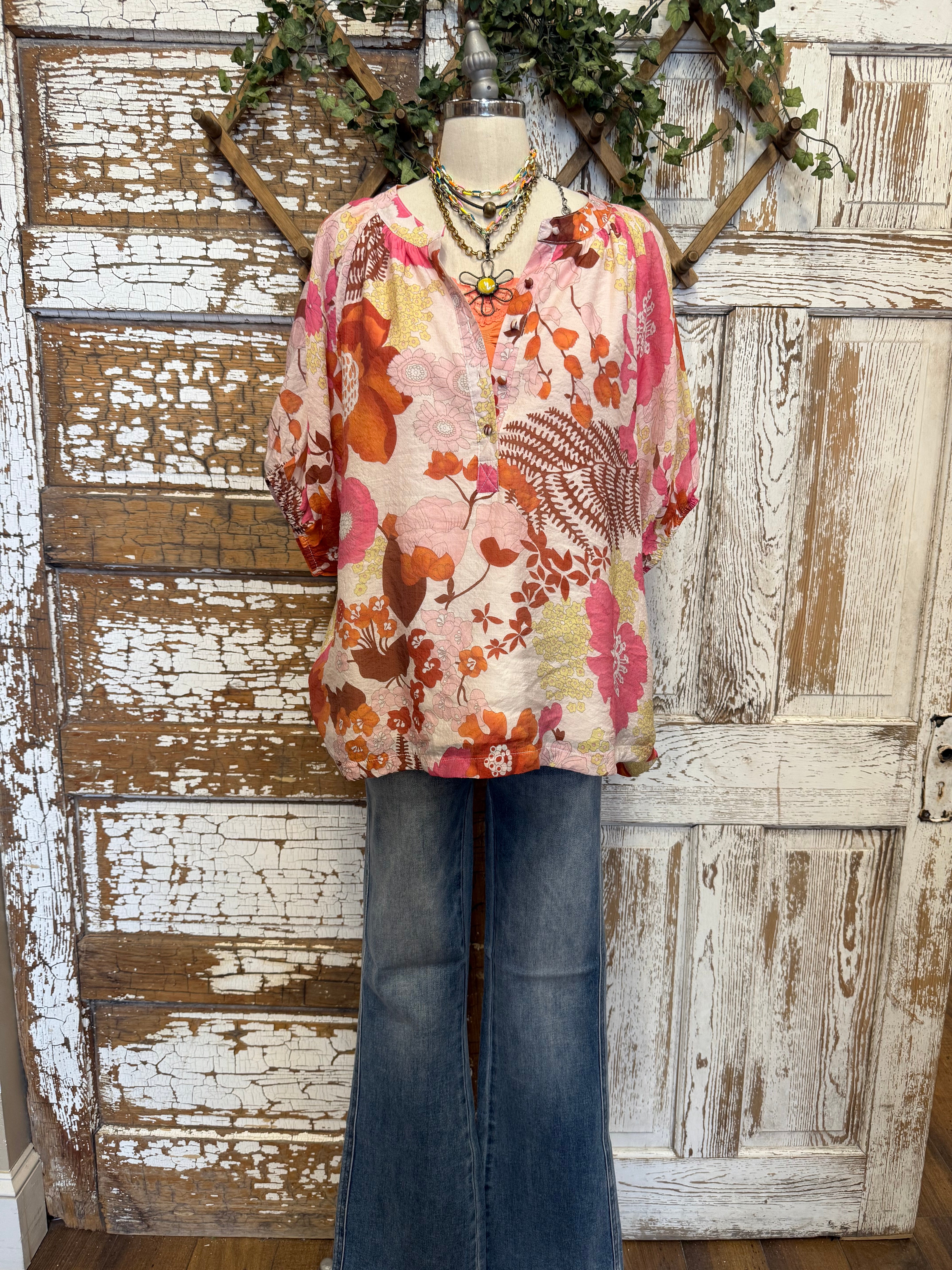 Mannequin wearing a floral blouse and jeans with handmade jewelry layers 