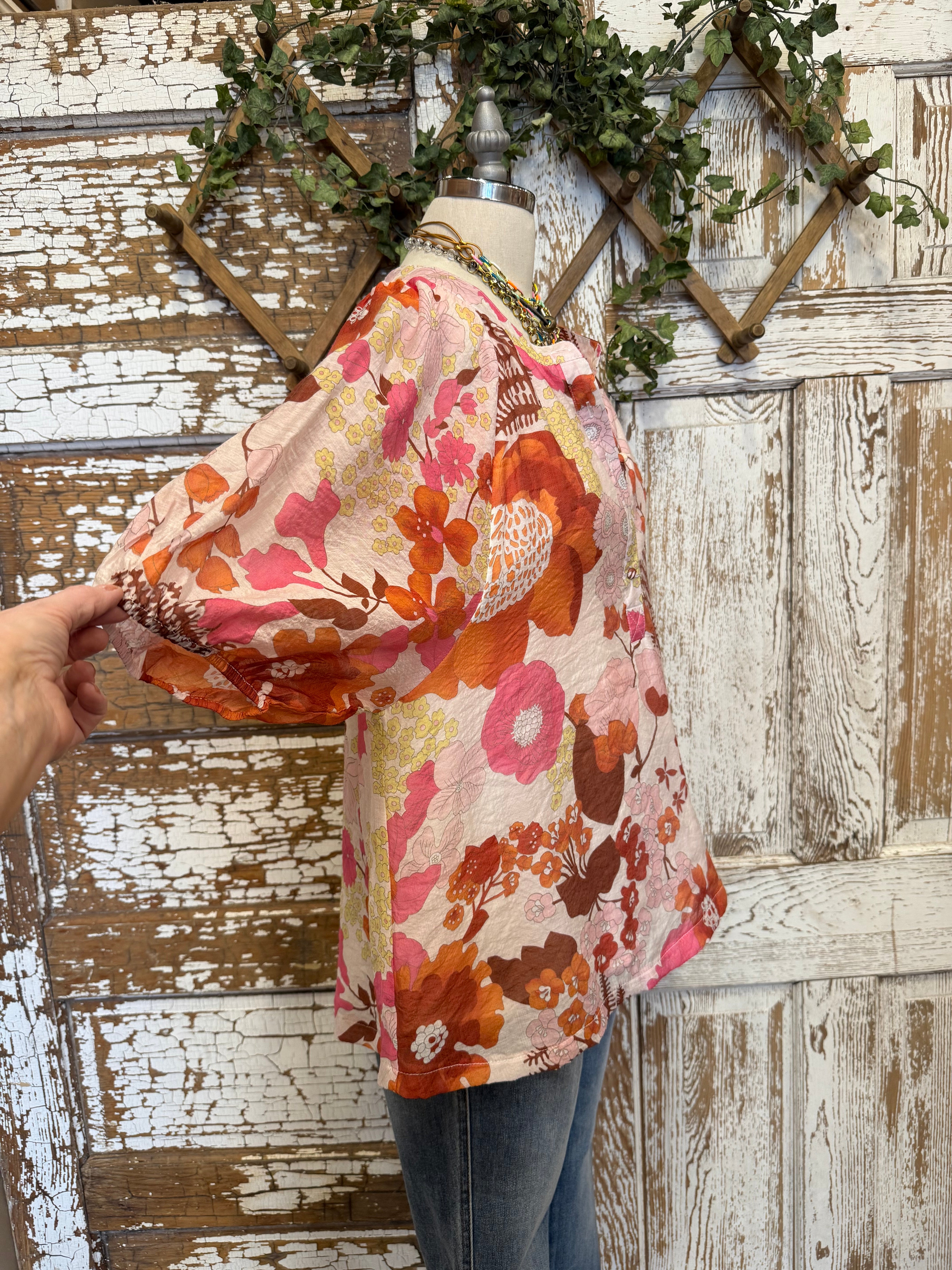 Mannequin wearing a floral blouse and jeans with handmade jewelry layers 