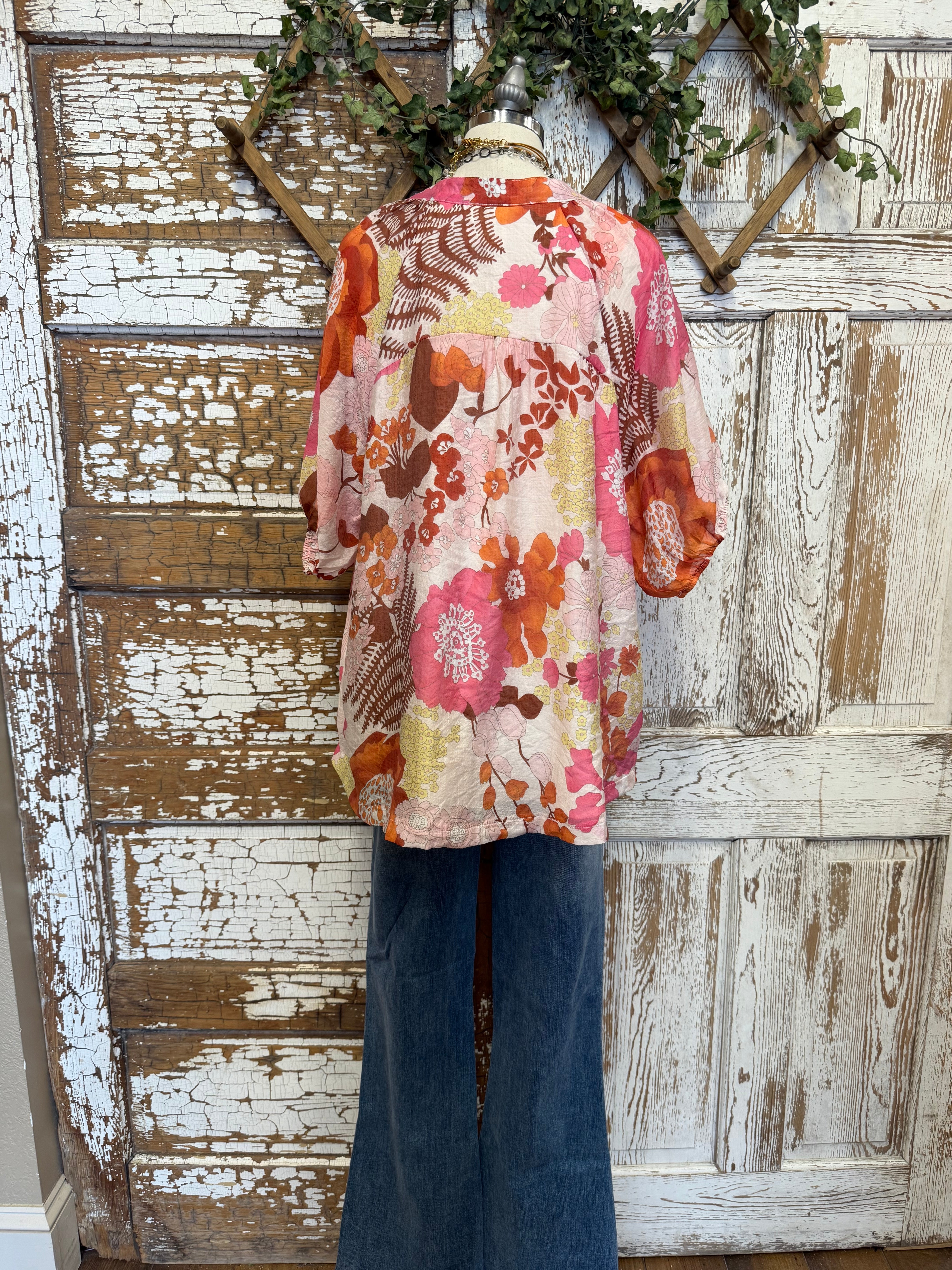 Mannequin wearing a floral blouse and jeans with handmade jewelry layers 