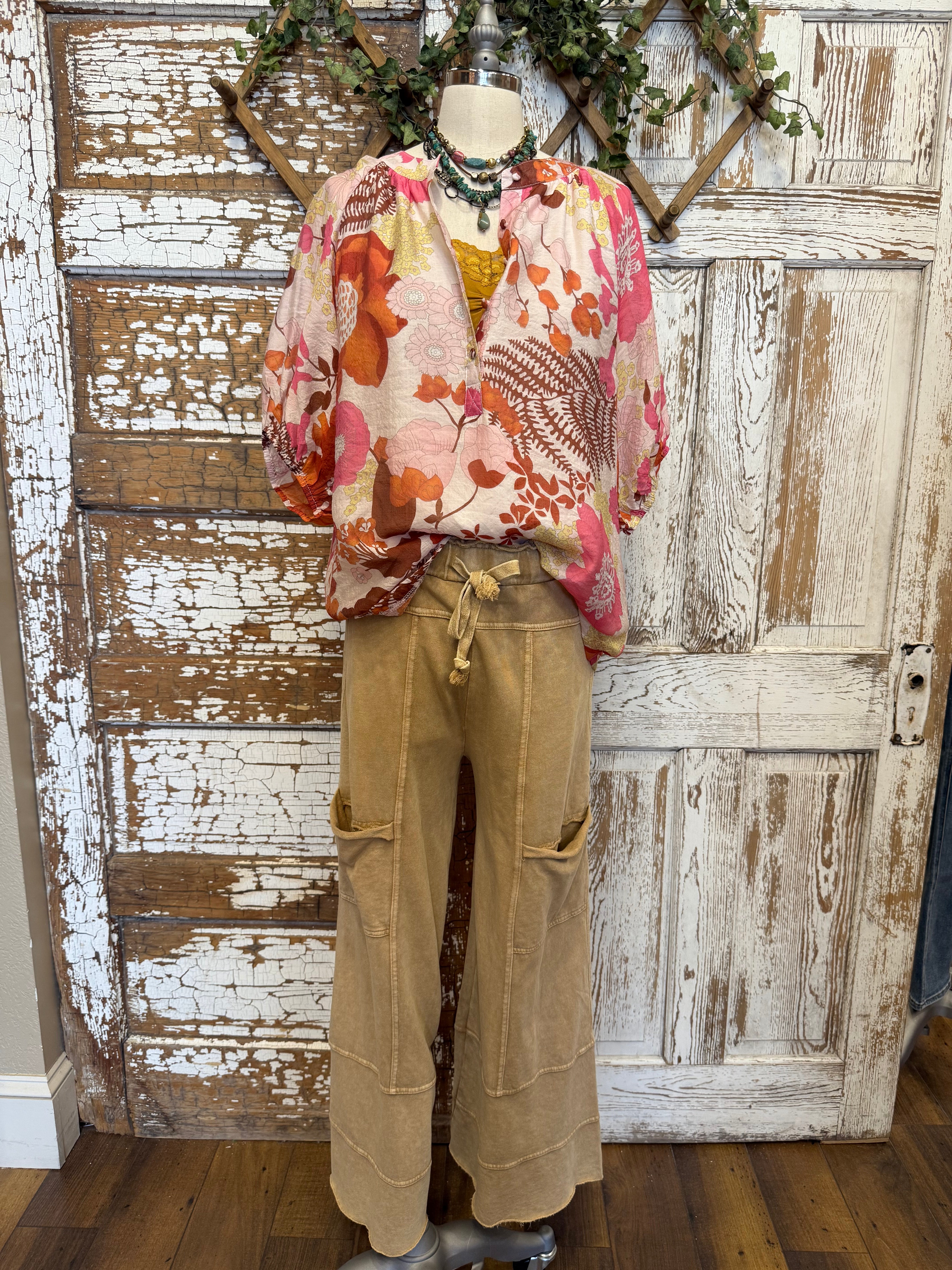 Mannequin wearing a floral blouse and leisurewear pants with handmade jewelry layers 