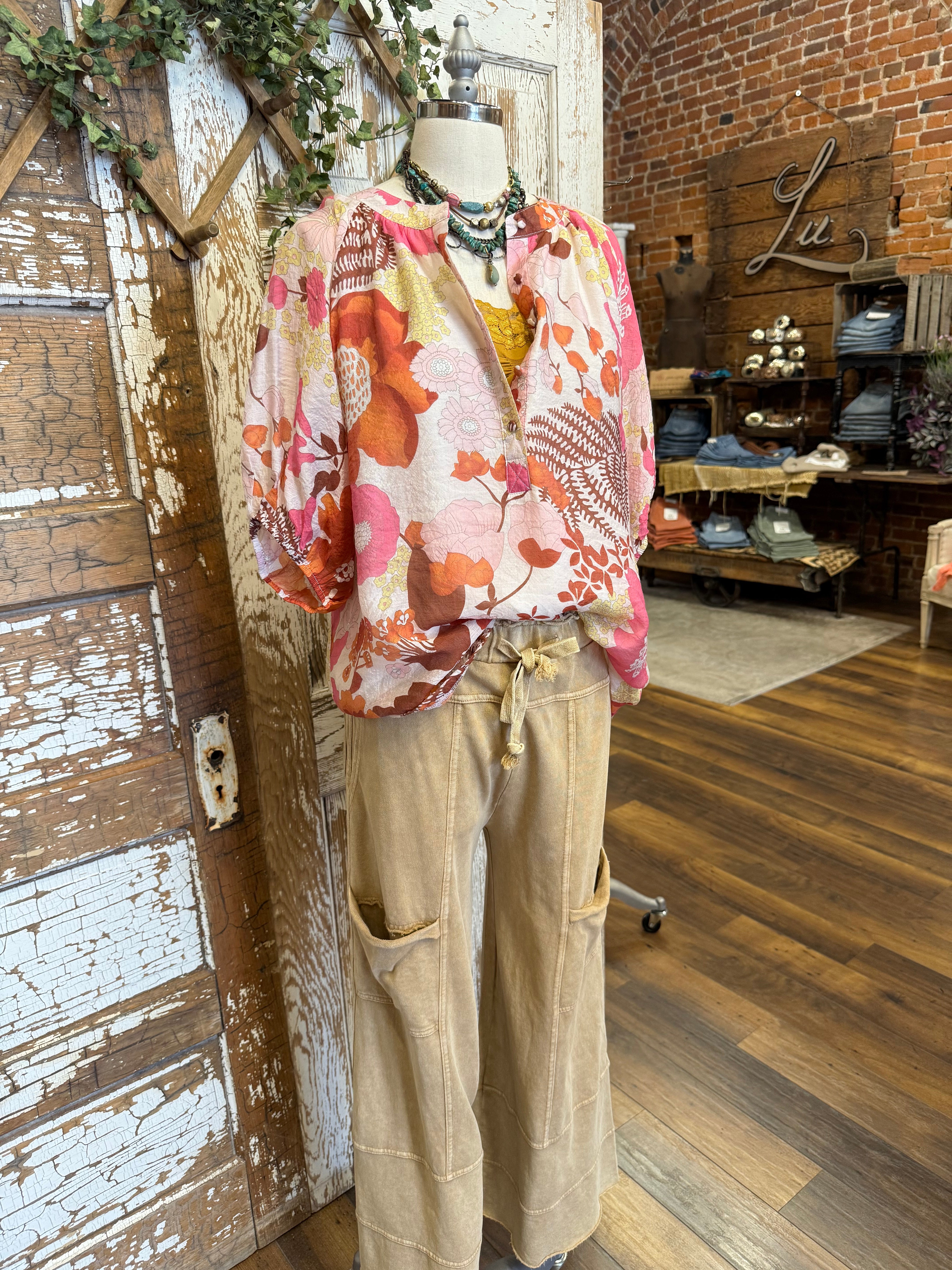 Mannequin wearing a floral blouse and leisurewear pants with handmade jewelry layers 