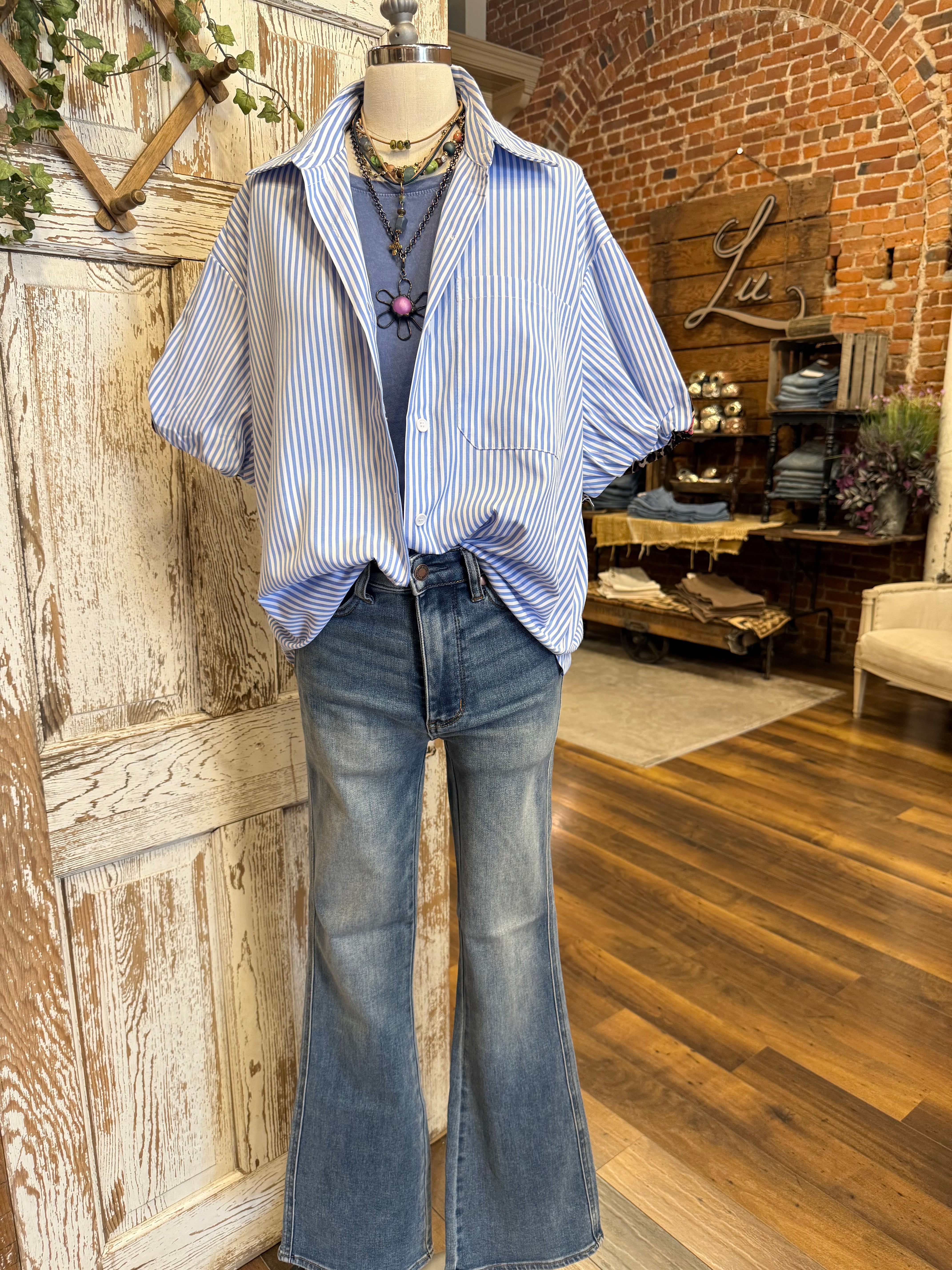 Mannequin wearing a blue striped shirt with pink and leopard detail and handmade jewelry and dark jeans in Springfield, MO boutique