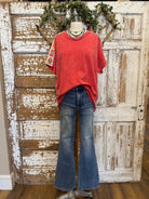 Poppy red shirt with handmade jewelry paired with jeans in boutique
