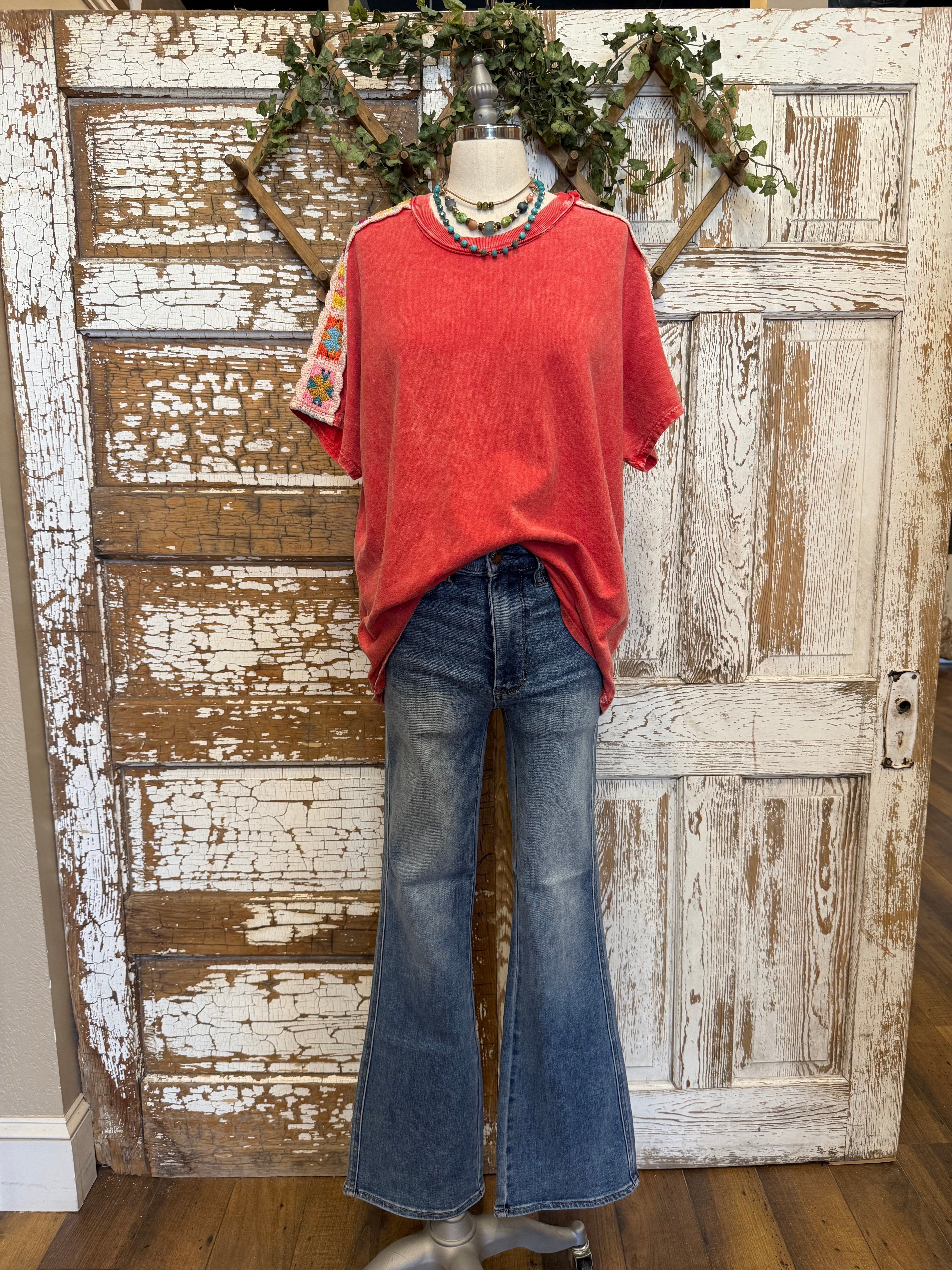 Poppy red shirt with handmade jewelry paired with jeans in boutique