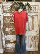 Poppy red shirt with handmade jewelry paired with jeans in boutique