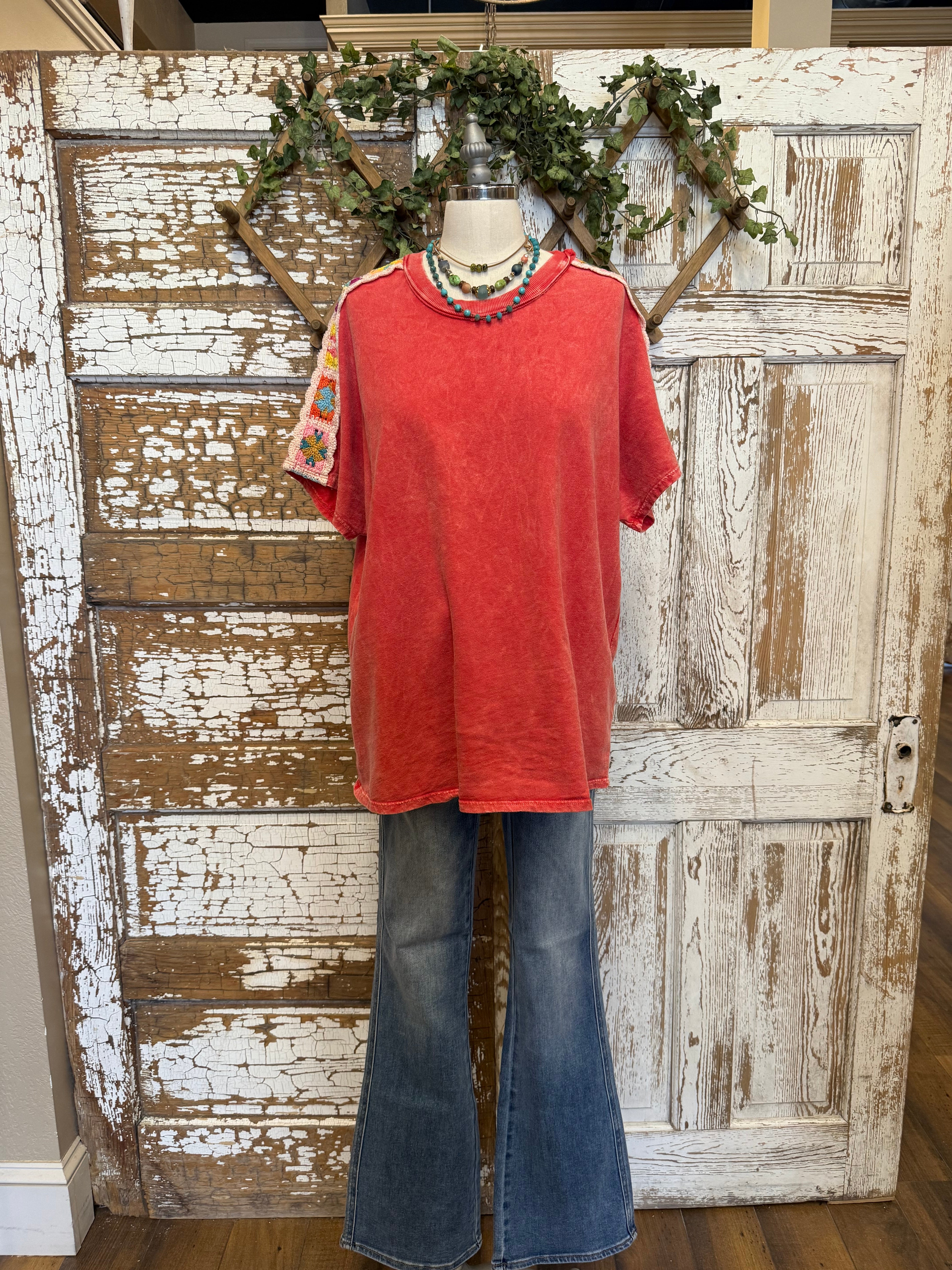 Poppy red shirt with handmade jewelry paired with jeans in boutique