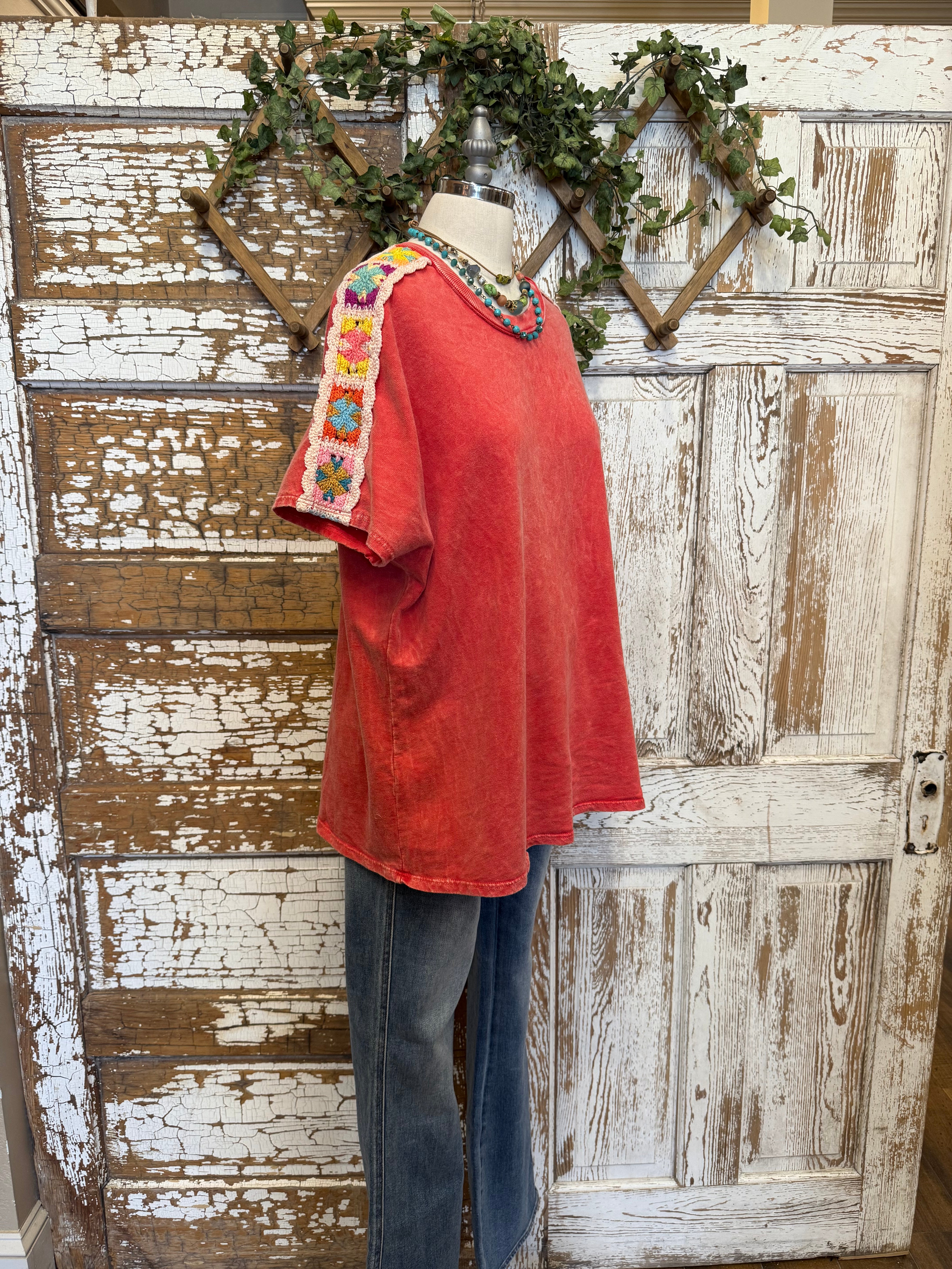 Poppy red shirt with handmade jewelry paired with jeans in boutique