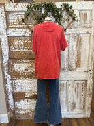 Poppy red shirt with handmade jewelry paired with jeans in boutique