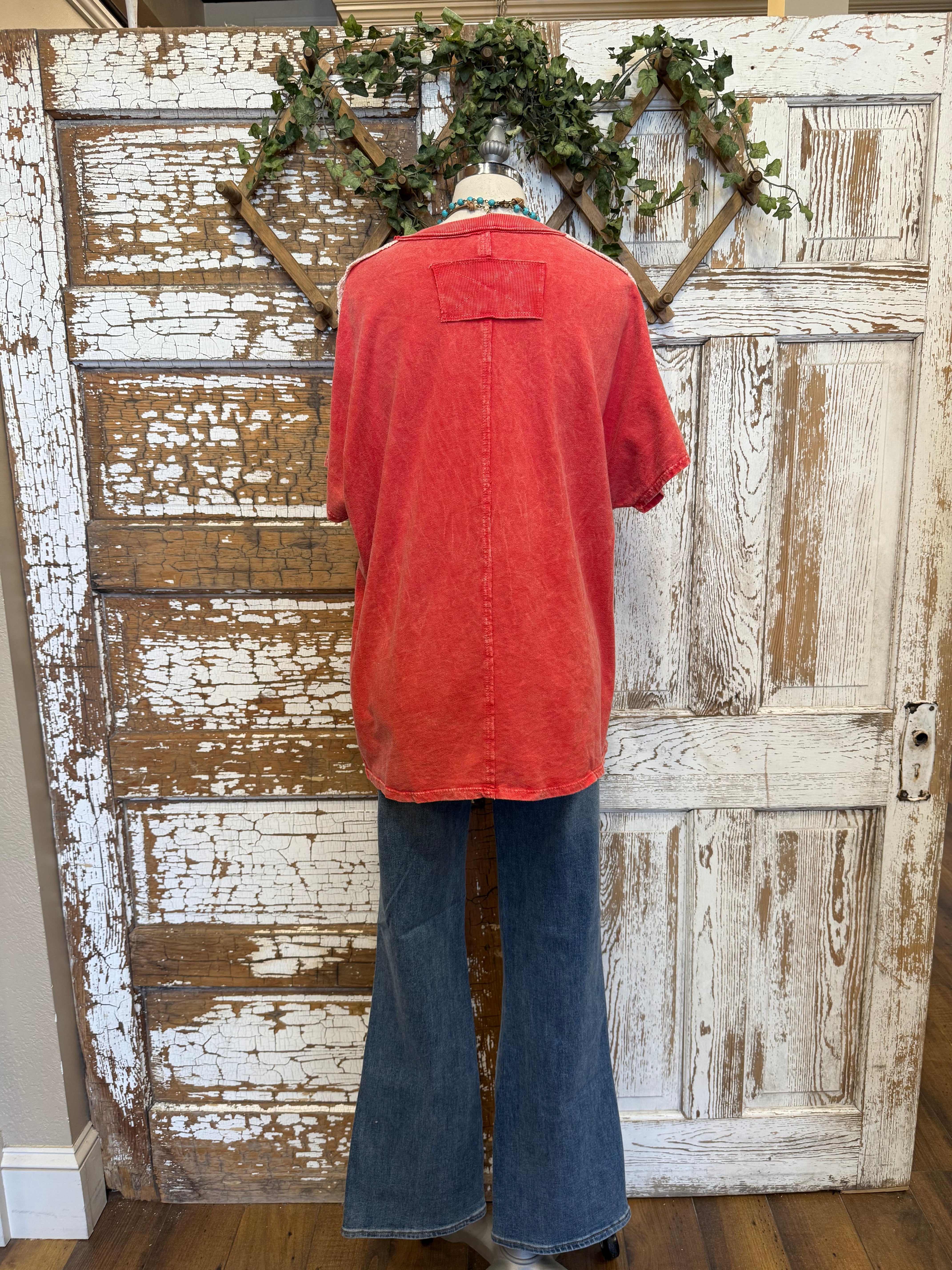 Poppy red shirt with handmade jewelry paired with jeans in boutique