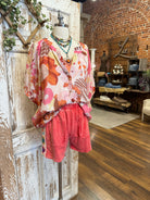 Mannequin wearing a floral blouse and leisurewear shorts with handmade jewelry layers 