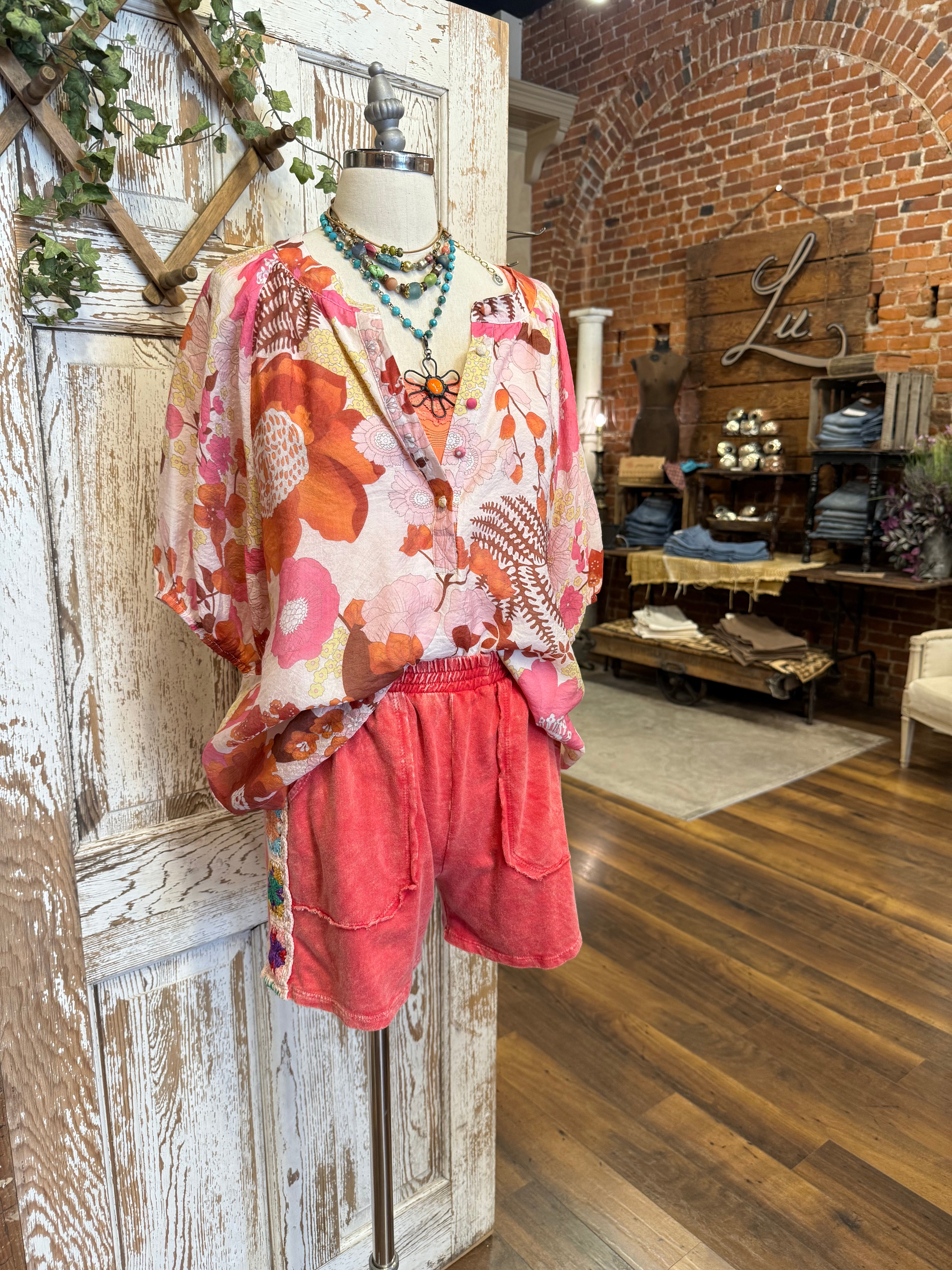 Mannequin wearing a floral blouse and leisurewear shorts with handmade jewelry layers 