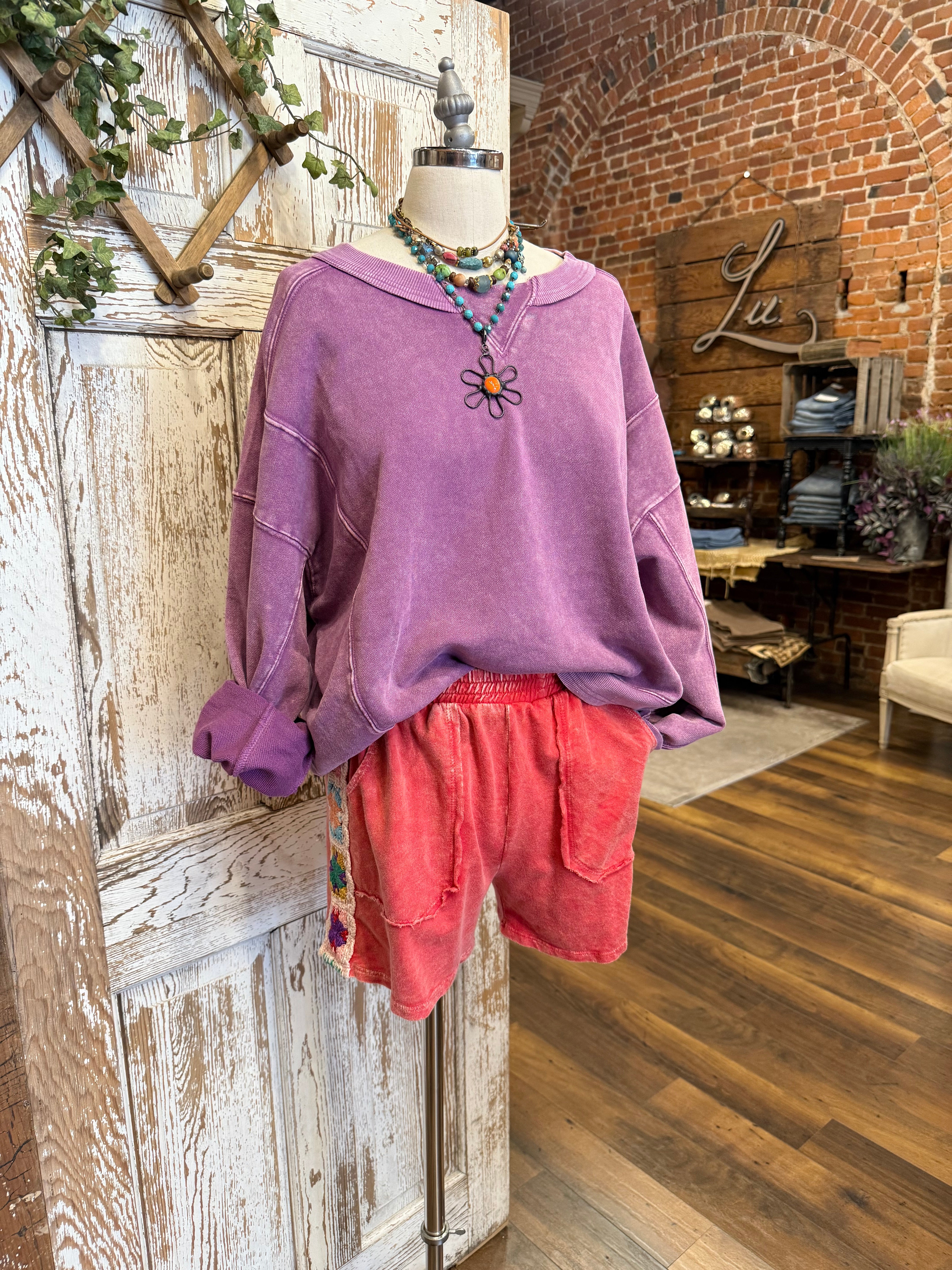 Mannequin wearing a purple sweatshirt and red shorts and handmade jewelry in Springfield, MO boutique