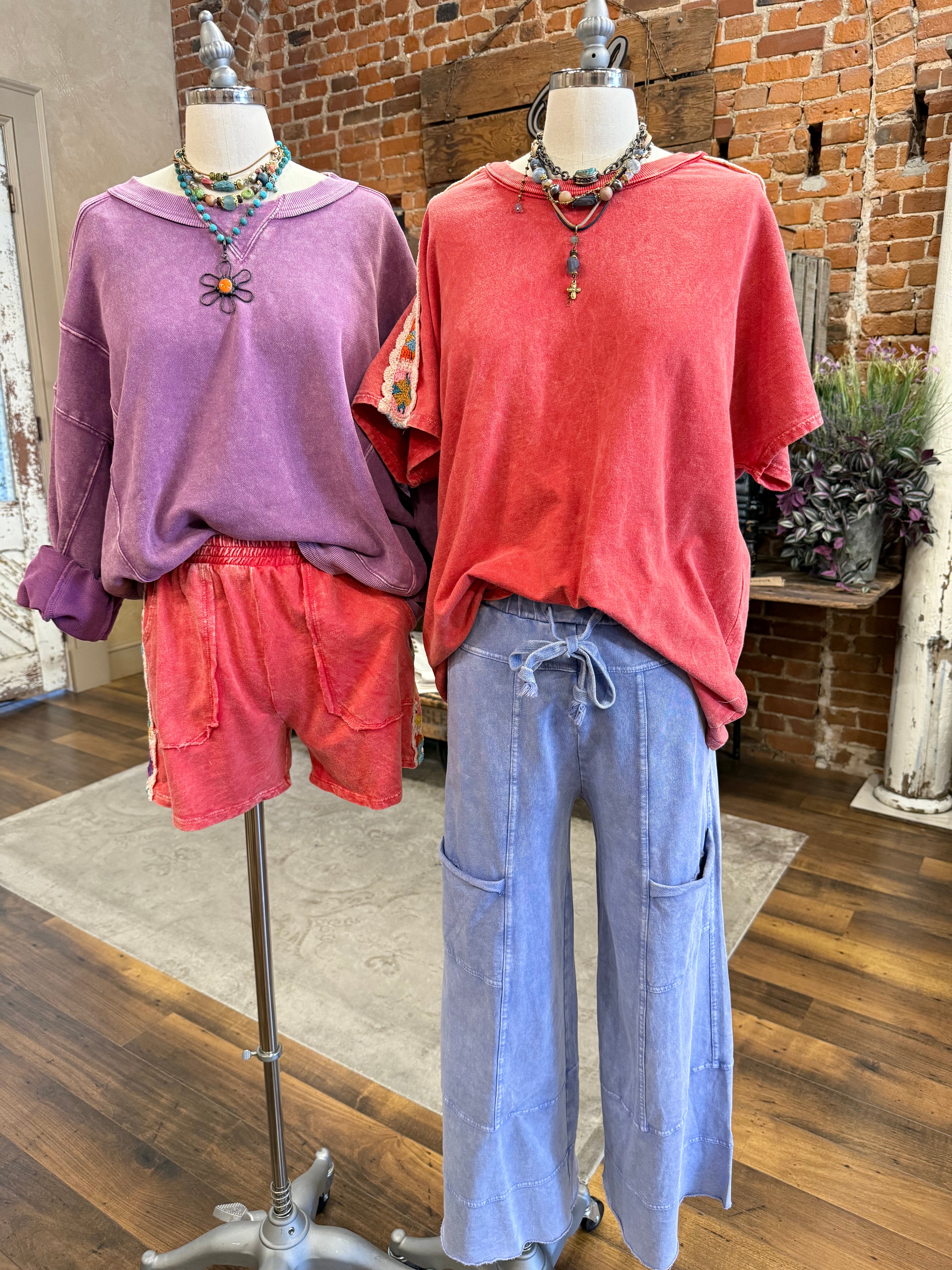 Mannequins wearing a purple sweatshirt and red shorts and handmade jewelry in Springfield, MO boutique