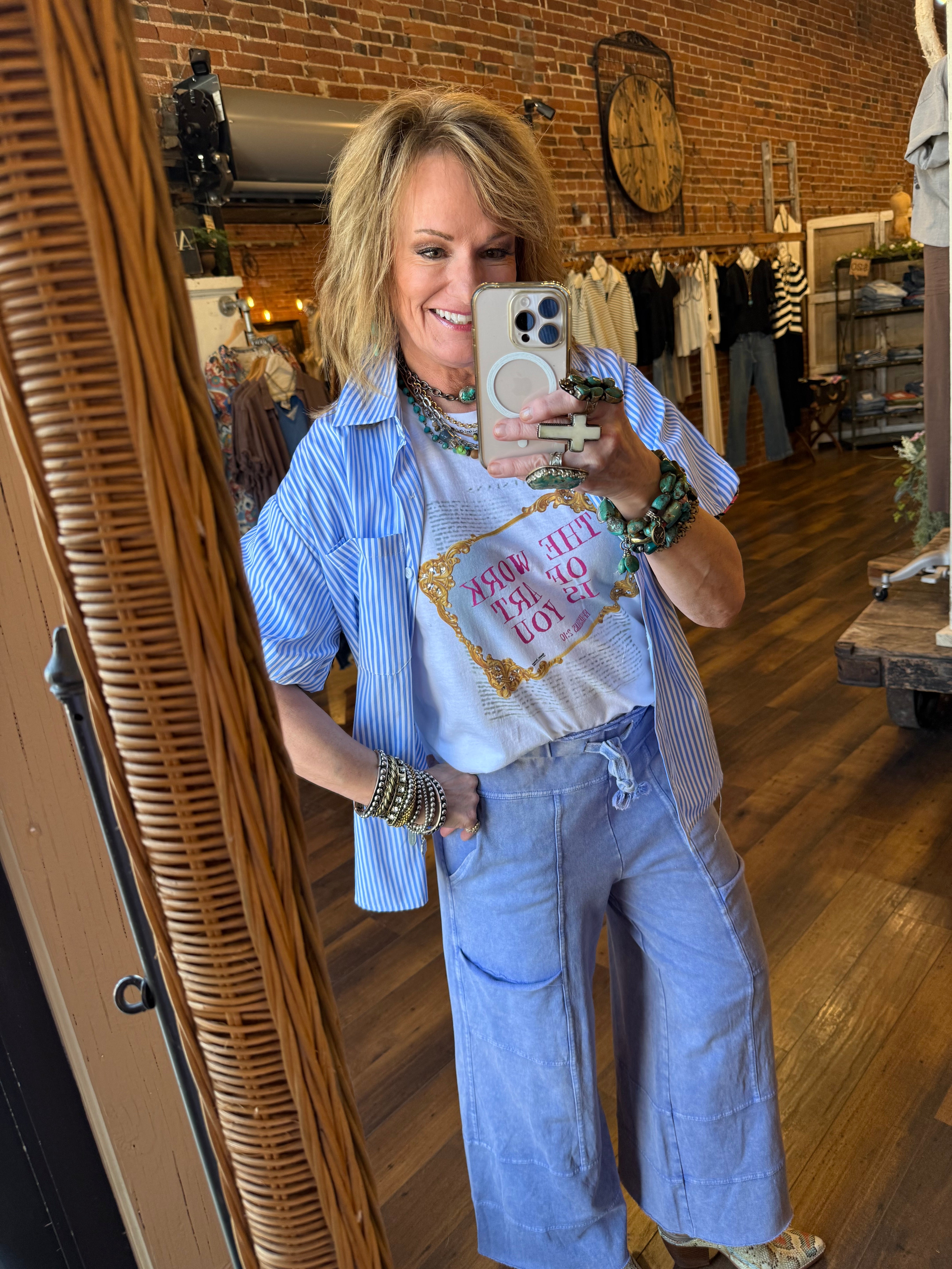Lu wearing graphic tee and loungewear leisurewear pants with lots of handmade jewelry and striped button up over shirt 