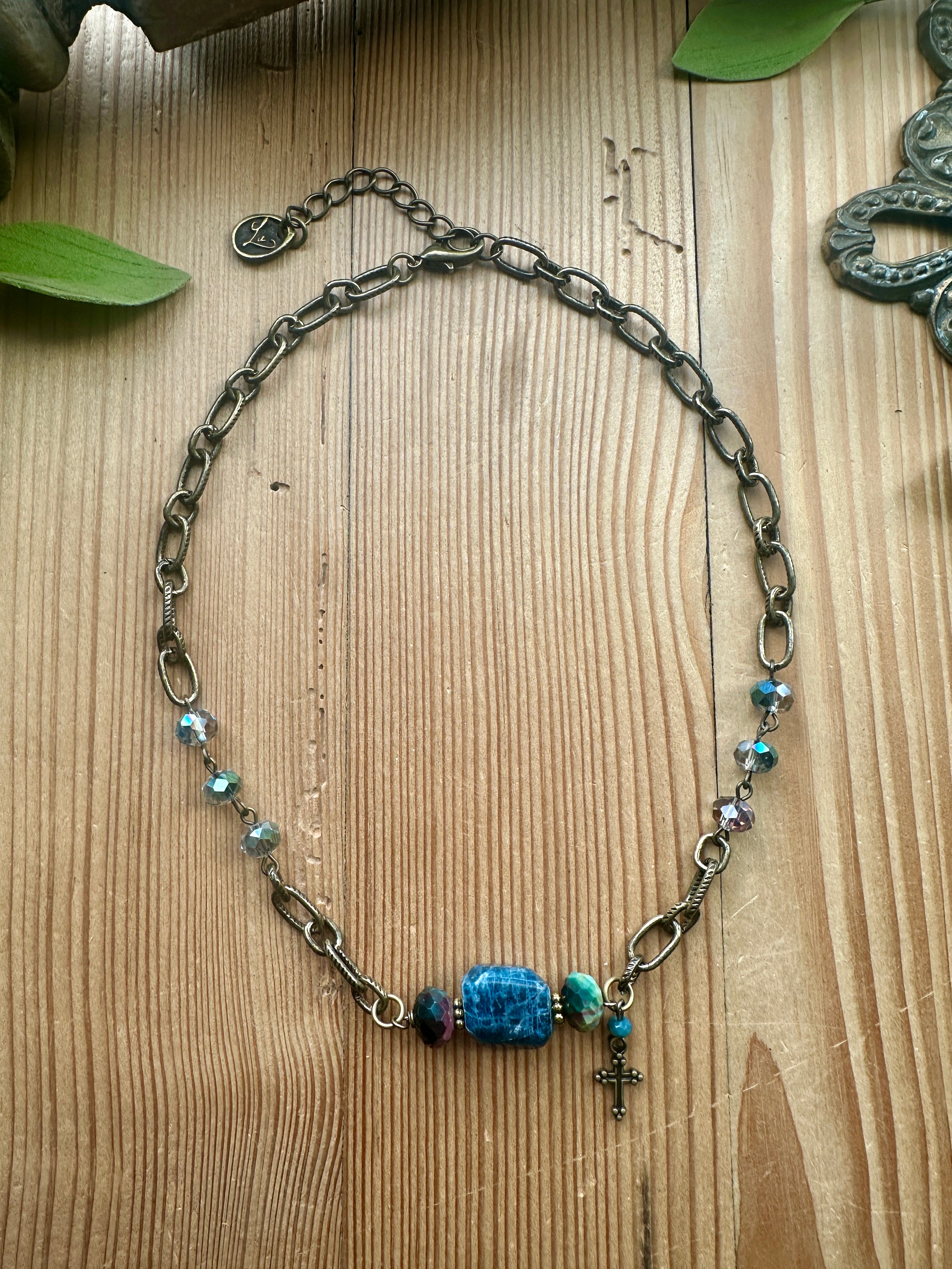 Blue Stone Cross Necklace by Artistic Works by Lu — antiqued brass chain necklace with a crackled blue stone focal bead, faceted crystal accents, and a dainty cross charm