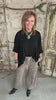 Lu wearing black flowy top and patterned leopard print pants against a rustic boutique springfield, mo